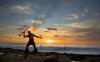 Fire dancer performing at sunset during Kaula-Luau in Hawaii.