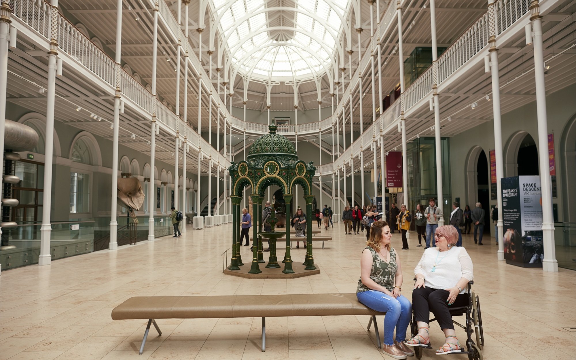Visitors inside the National Museum of Scotland, Edinburgh, with a decorative green fountain centerpiece.