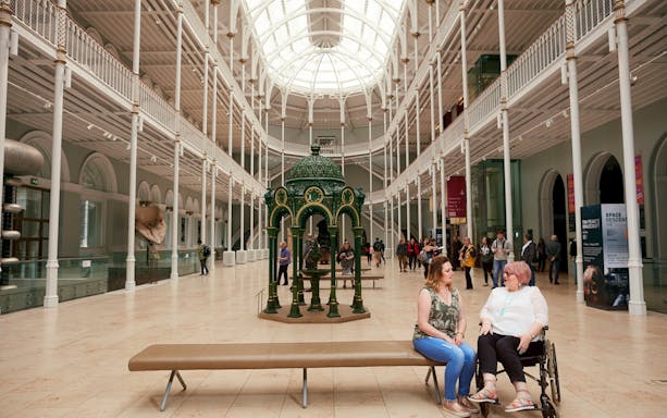 Visitors inside the National Museum of Scotland, Edinburgh, with a decorative green fountain centerpiece.