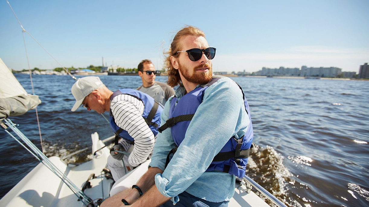 Tourists yachting with friends in life jackets, enjoying a scenic tour.