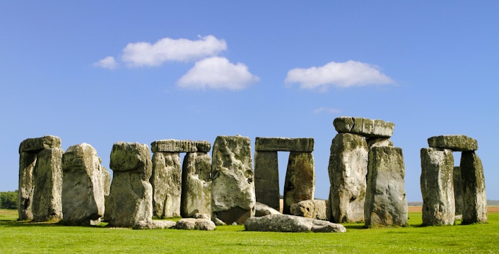 Stonehenge stone circle under blue sky during daytime in Wiltshire, England.
