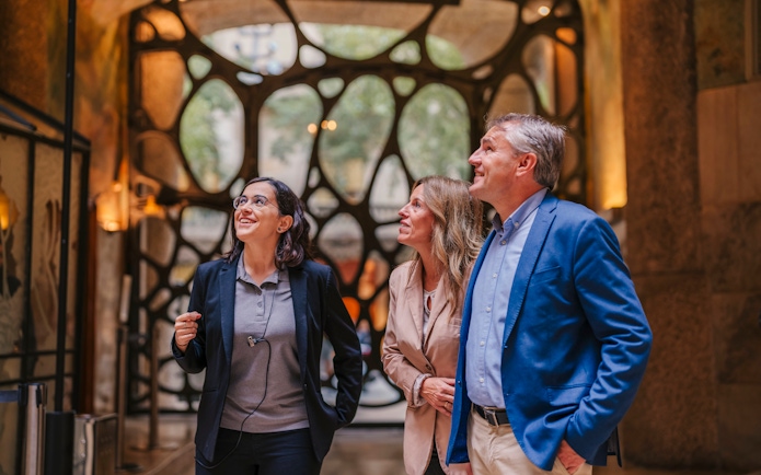 Tourist group with guide inside Casa Mila, Barcelona, admiring architecture.