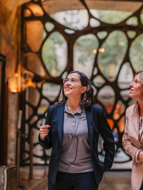 Tourist group with guide inside Casa Mila, Barcelona, admiring architecture.