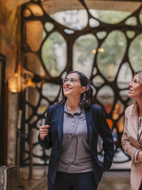 Tourist group with guide inside Casa Mila, Barcelona, admiring architecture.