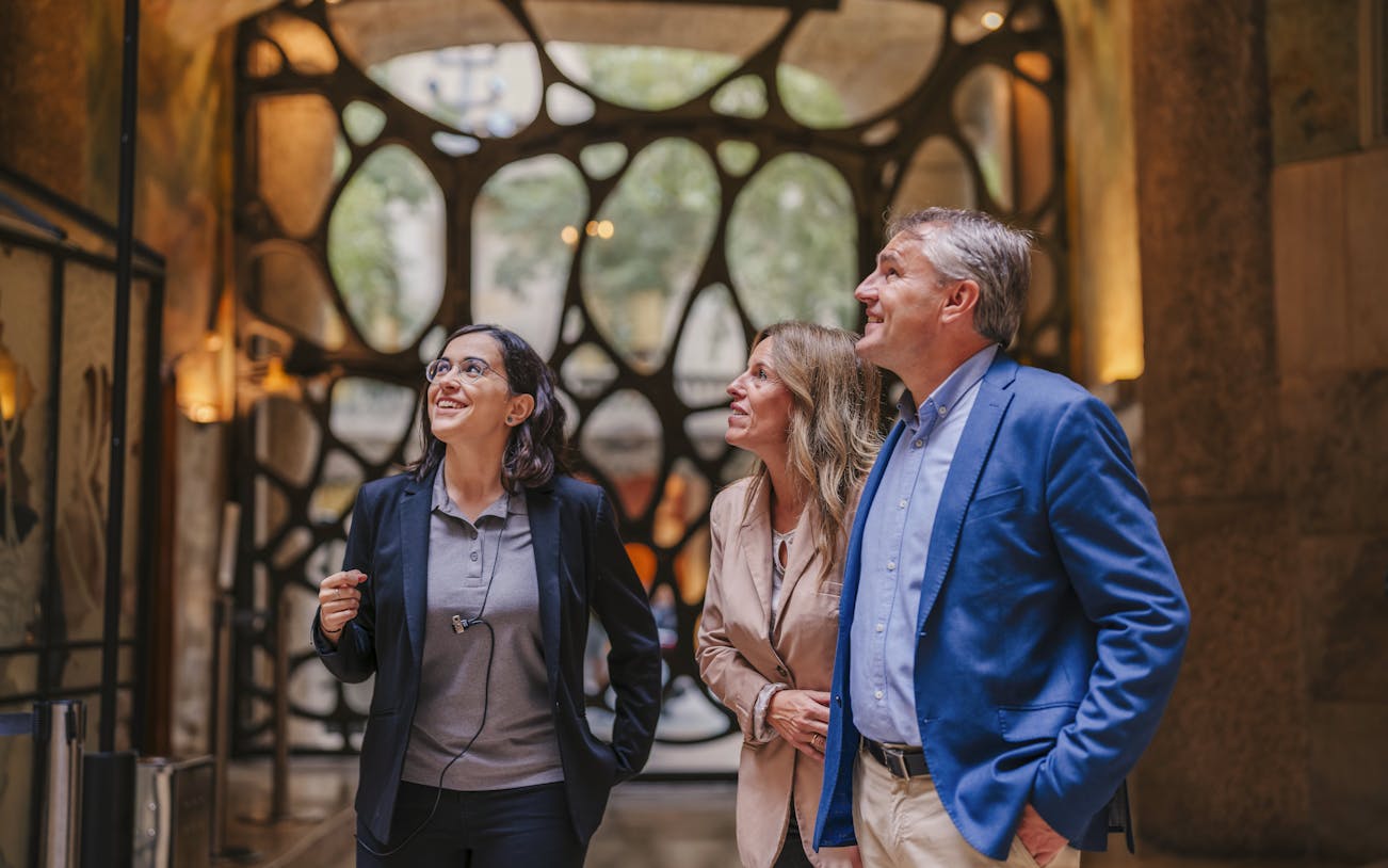 Tourist group with guide inside Casa Mila, Barcelona, admiring architecture.