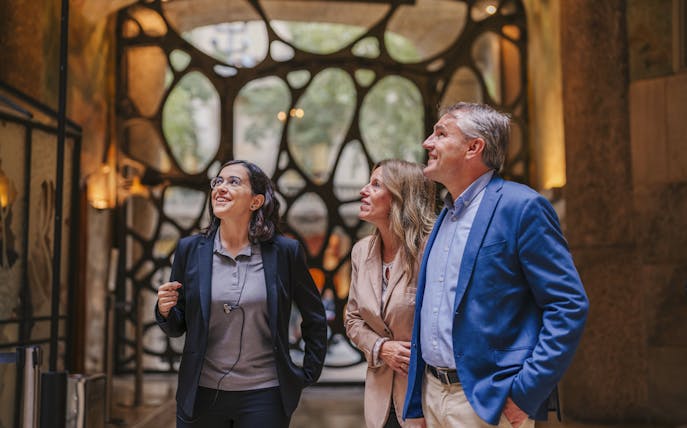 Tourist group with guide inside Casa Mila, Barcelona, admiring architecture.