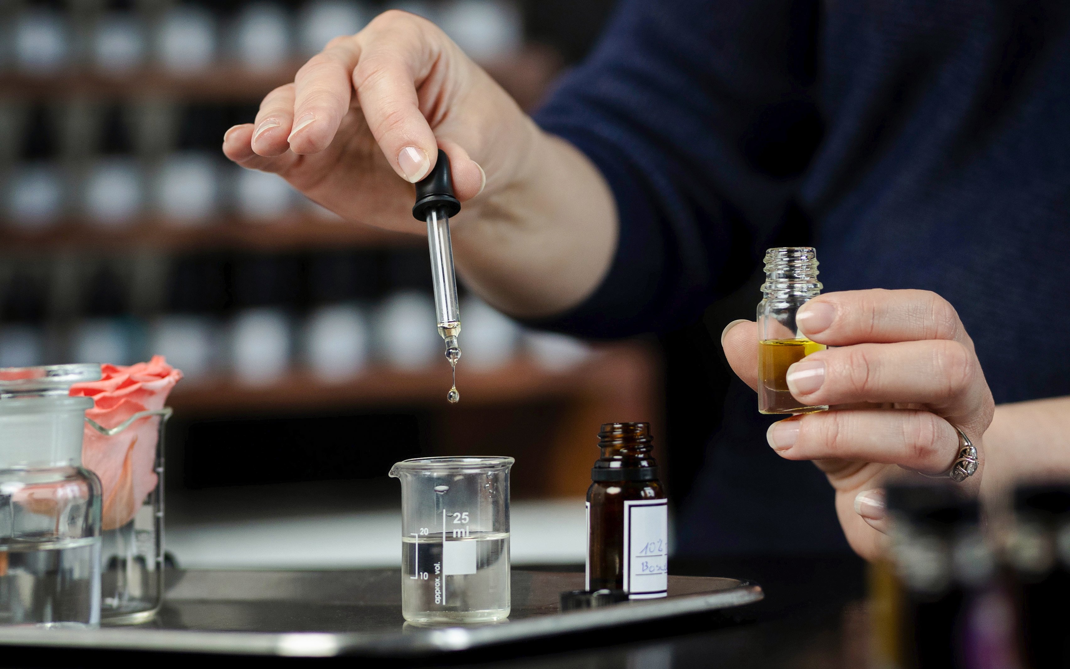 Mixing fragrances with a dropper into a small bottle.