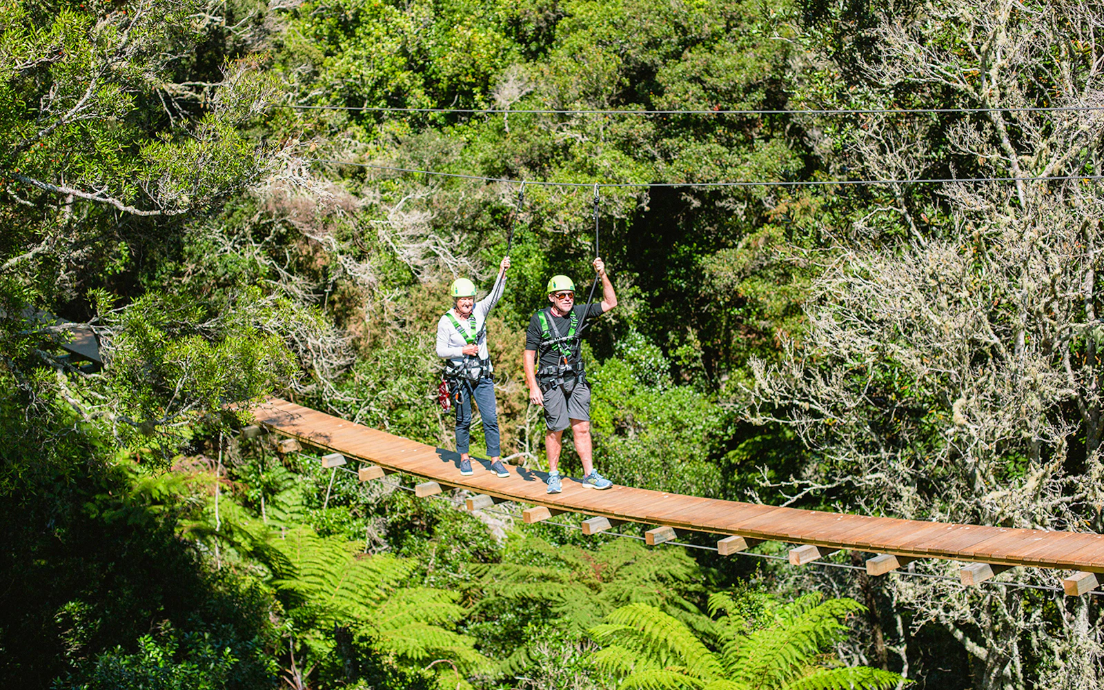 Two people crossing a suspension bridge in Rotorua forest during a zipline tour.
