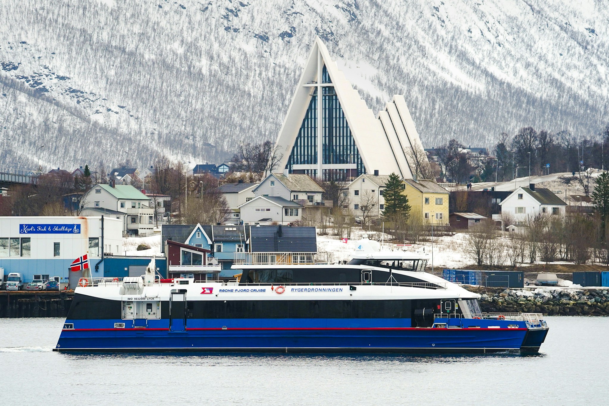 Cruise ship near Arctic Cathedral in Tromsø, Norway, with snowy mountains in the background.