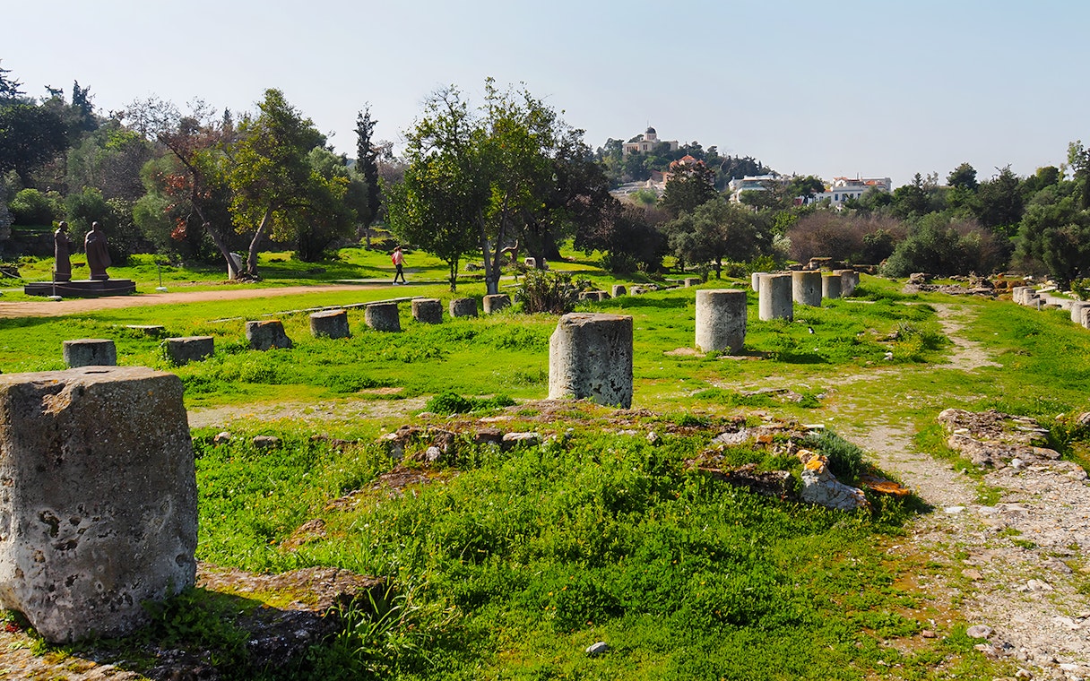 Ancient Agora ruins with stone columns and greenery, Athens, Greece.
