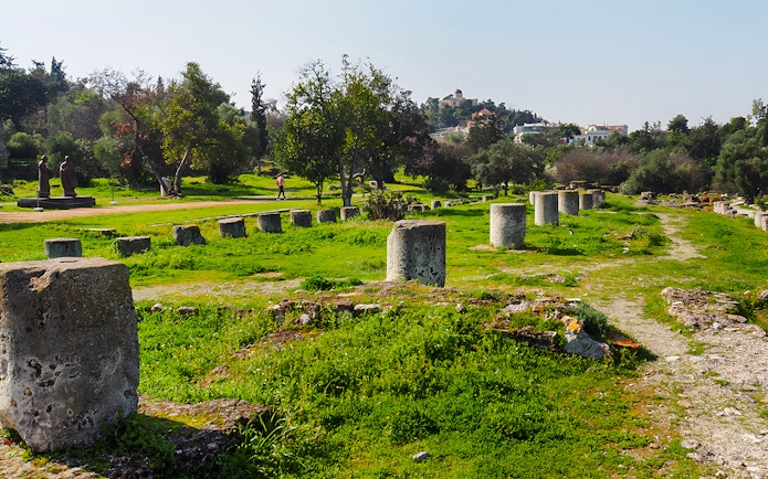 Ancient Agora ruins with stone columns and greenery, Athens, Greece.