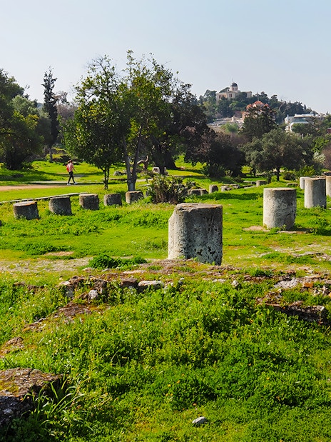 Ancient Agora ruins with stone columns and greenery, Athens, Greece.