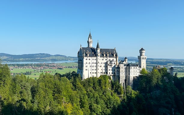 Neuschwanstein Castle surrounded by lush greenery, view from the full-day tour from Munich.