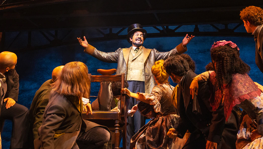 Performer in top hat engaging audience during Sweeney Todd musical scene.