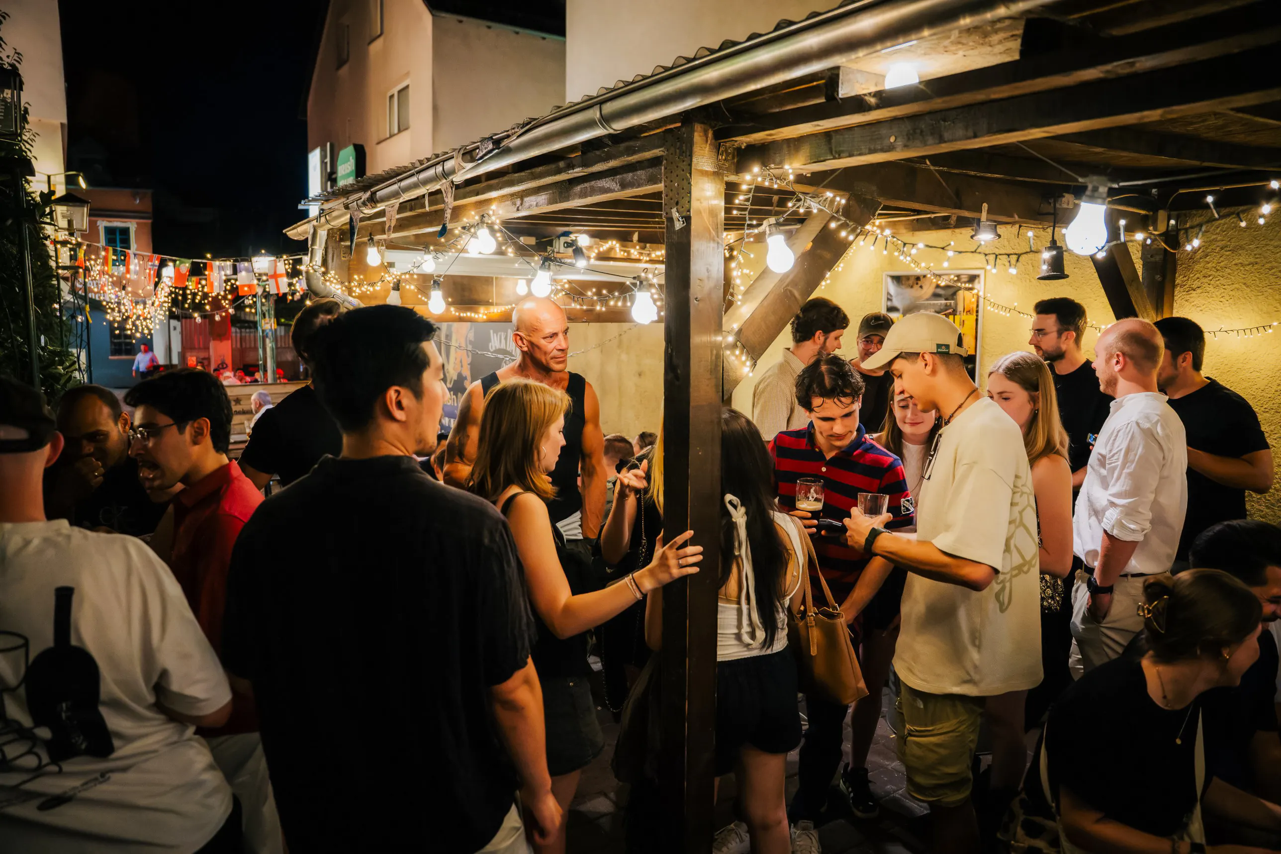 Group enjoying Berlin nightlife tour at an outdoor venue with string lights.