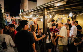 Group enjoying Berlin nightlife tour at an outdoor venue with string lights.
