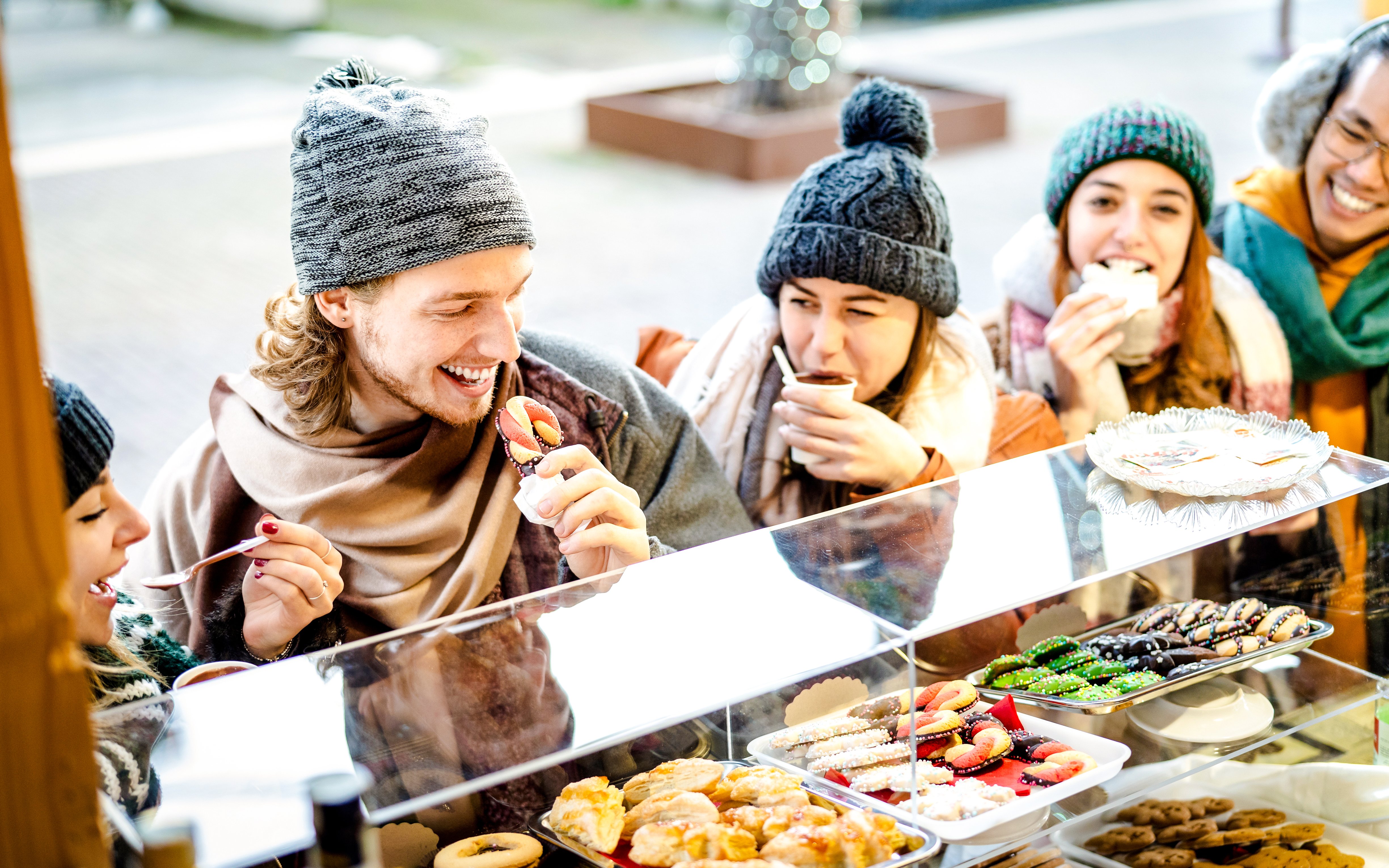 Friends enjoying snacks at a Christmas market food stall.