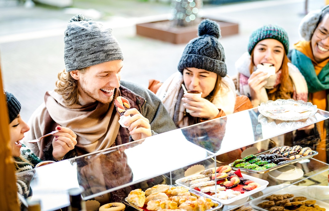 Friends enjoying snacks at a Christmas market food stall.