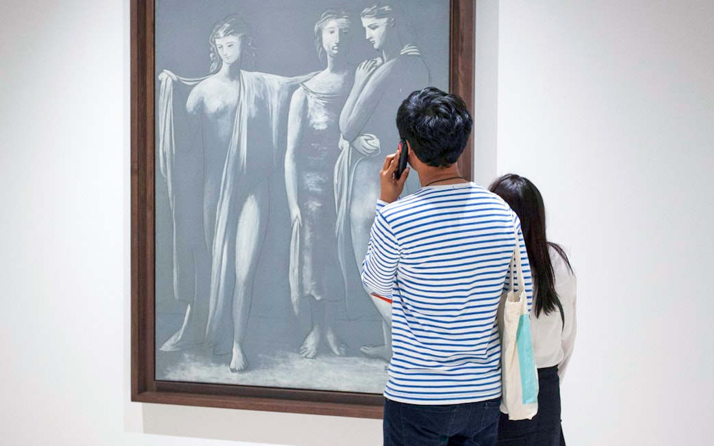 Visitor using audio guide in front of Picasso artwork at Picasso Museum Malaga.