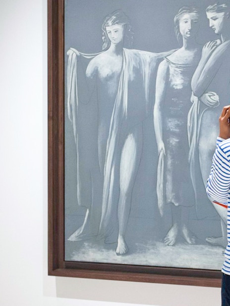 Visitor using audio guide in front of Picasso artwork at Picasso Museum Malaga.