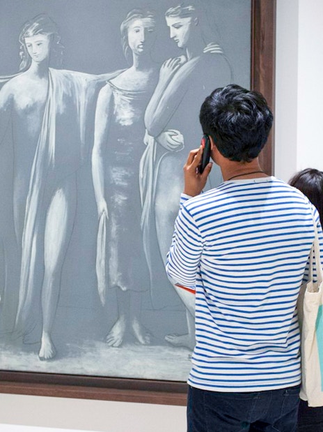 Visitor using audio guide in front of Picasso artwork at Picasso Museum Malaga.