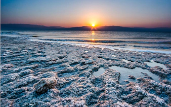 Sunrise over the Dead Sea with salt formations on the shore, Amman half-day trip.