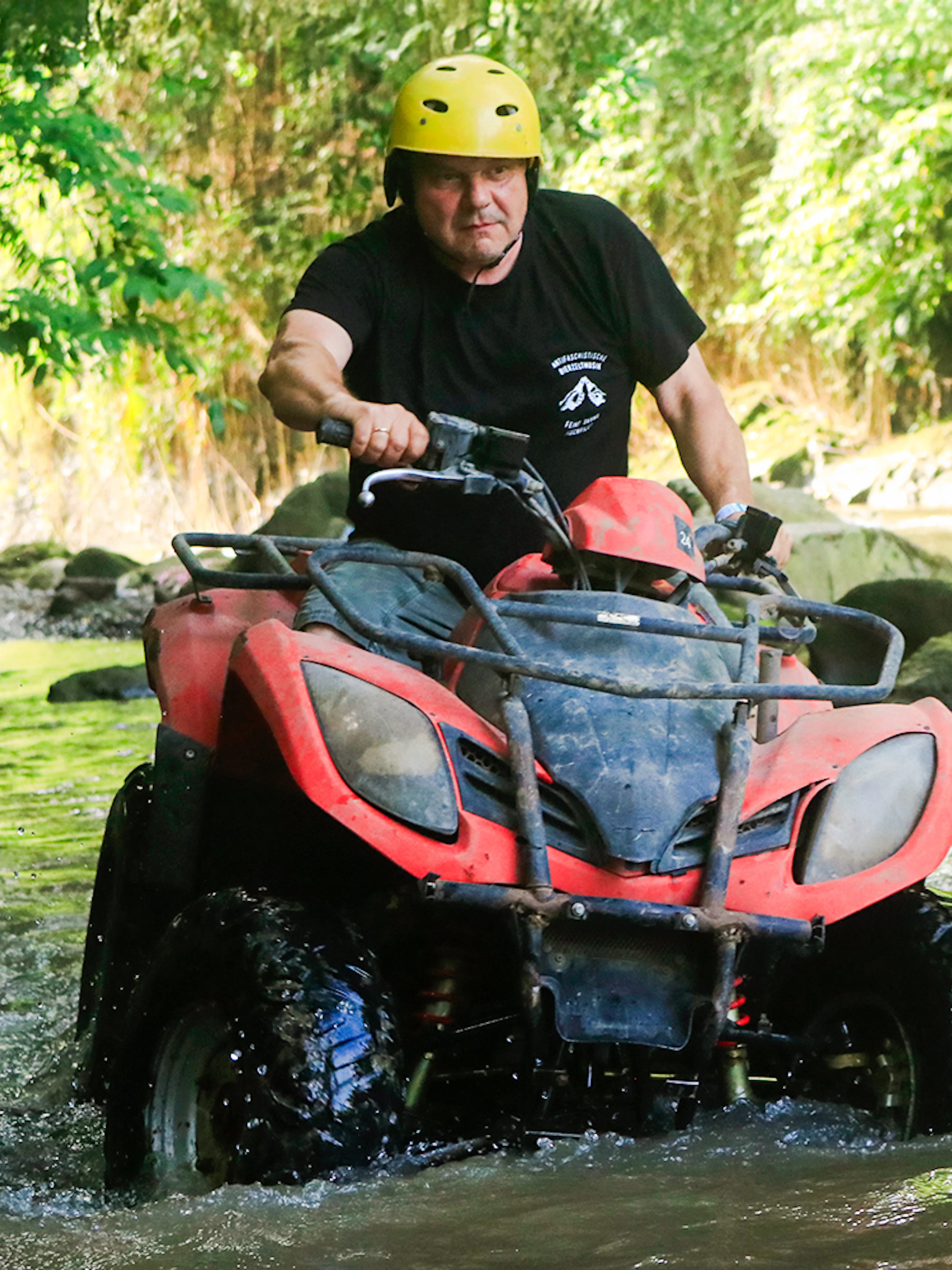 ATV navigating a rocky stream in Bali jungle.