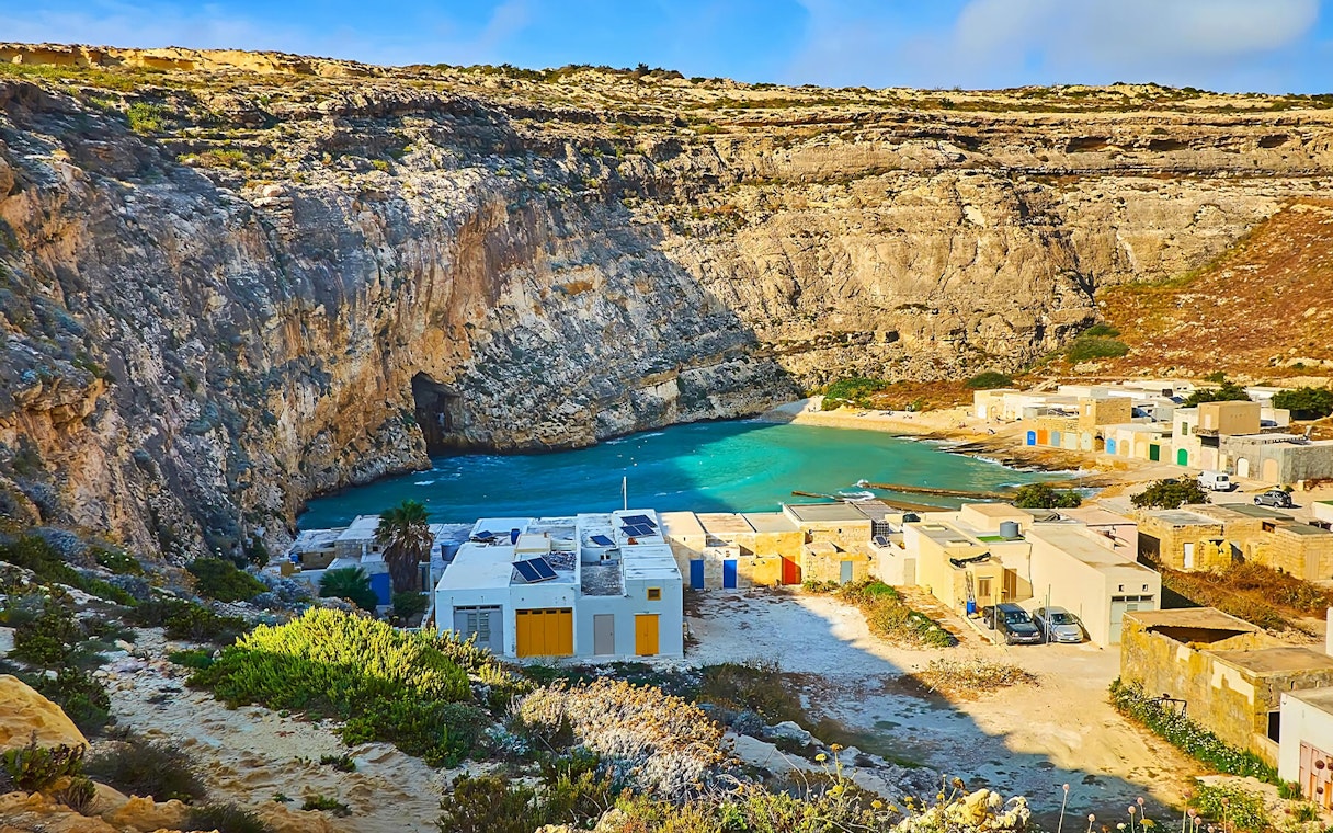 Gozo's Dwejra Bay with limestone cliffs and traditional Maltese buildings.