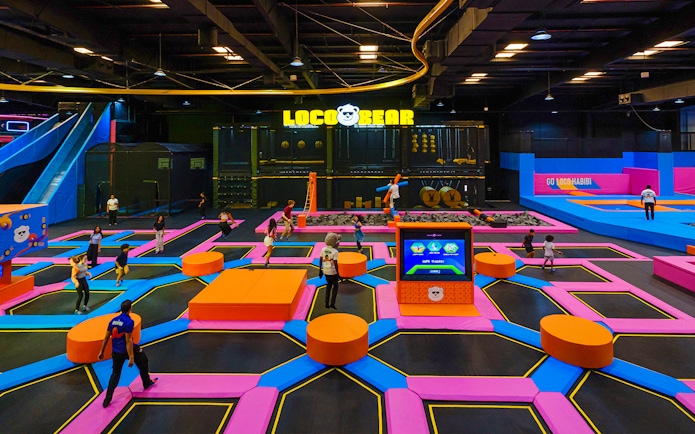 Indoor trampoline park at Loco Bear entertainment hub with people jumping and playing.