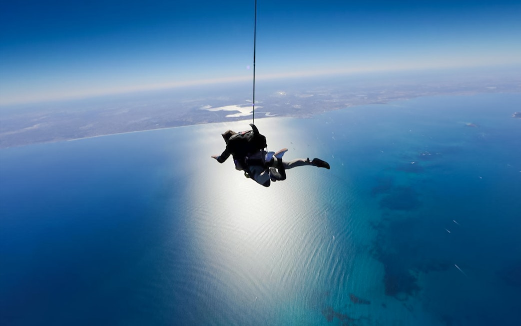 Tandem skydivers freefall over Rottnest Island's coastline.