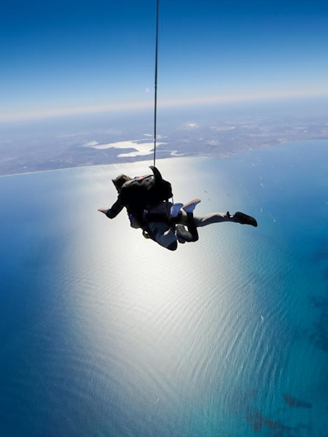 Tandem skydivers freefall over Rottnest Island's coastline.
