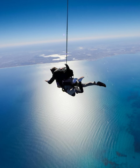 Tandem skydivers freefall over Rottnest Island's coastline.