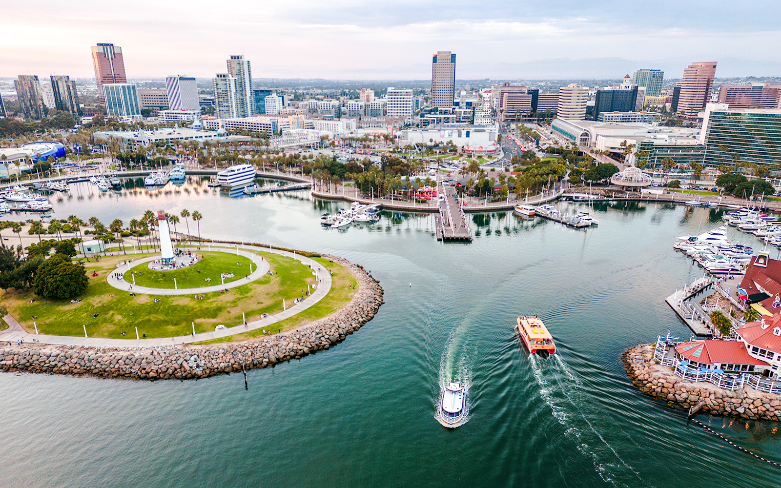 Aerial view of Downtown Long Beach CA at dusk with boats near Shoreline Aquatic Park.
