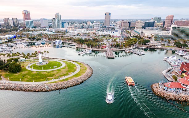 Aerial view of Downtown Long Beach CA at dusk with boats near Shoreline Aquatic Park.