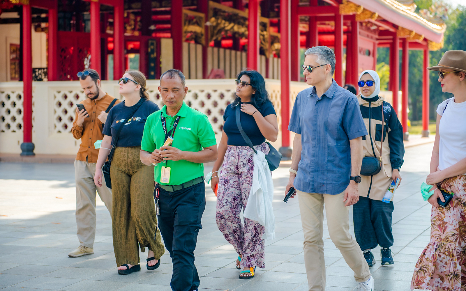 Tour guide leading tourists through Ayutthaya Historical Park, Thailand.