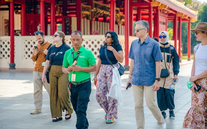 Tour guide leading tourists through Ayutthaya Historical Park, Thailand.