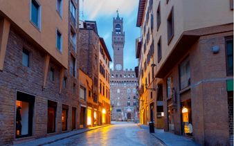 Florence street view with Palazzo Vecchio tower at dusk, part of haunted city exploration game.