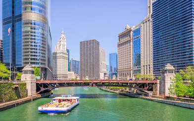 Chicago River cruise boat passing iconic skyscrapers and bridges.