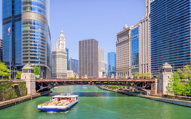 Chicago River cruise boat passing iconic skyscrapers and bridges.