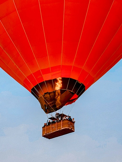 Hot air balloon flying over Luxor with passengers in the basket.