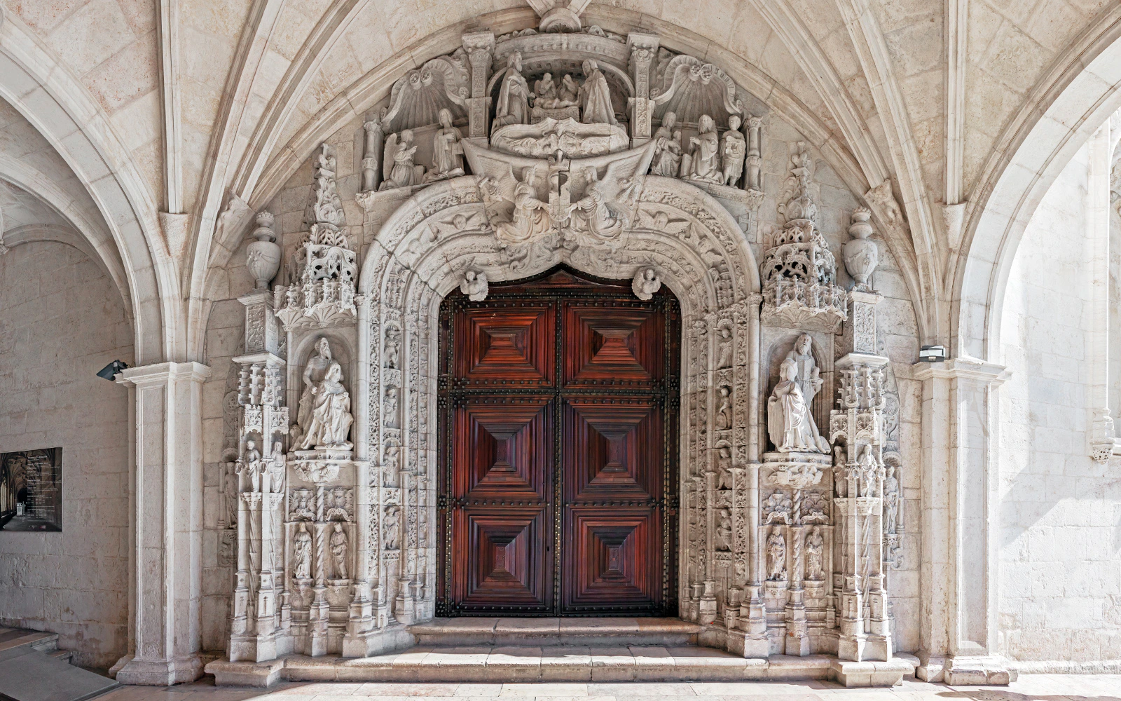 Jeronimos Monastery’s South Portal with intricate stone carvings and wooden doors in Lisbon, Portugal.