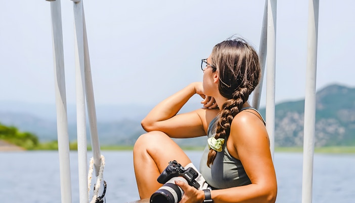 Tourist with camera on a boat at Lake Skadar, Montenegro.
