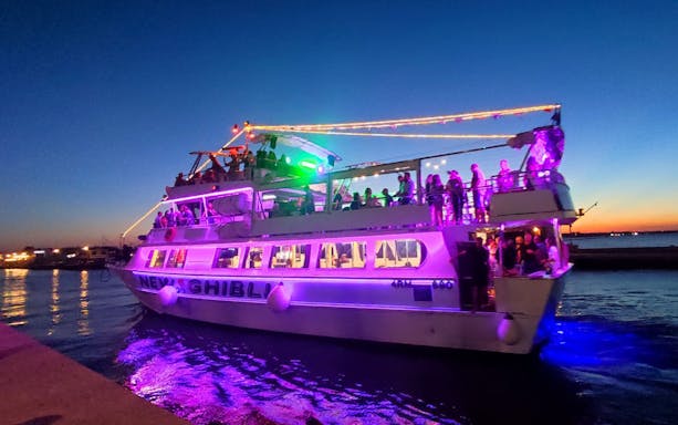 Boat with colorful lights and passengers during Riviera Romagnola half-day tour at sunset.