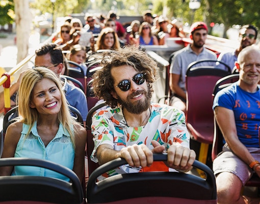 Red double-decker bus on a New Orleans street, part of the City Sightseeing 1-Day Hop-On Hop-Off Bus Tour.