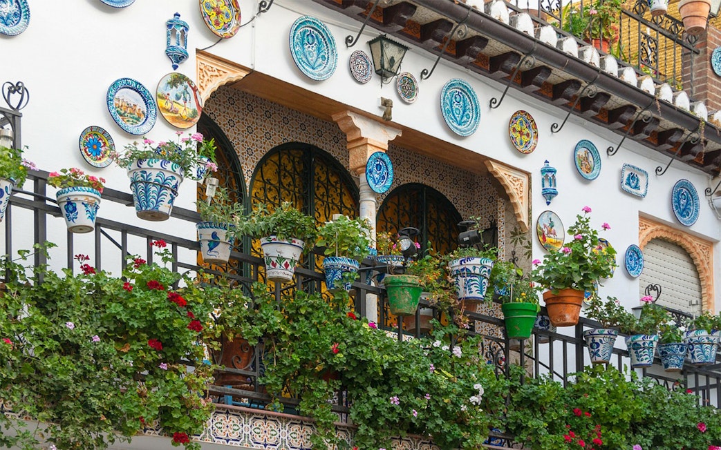 Ornate balcony with colorful ceramic plates and potted plants in Granada, Alhambra.