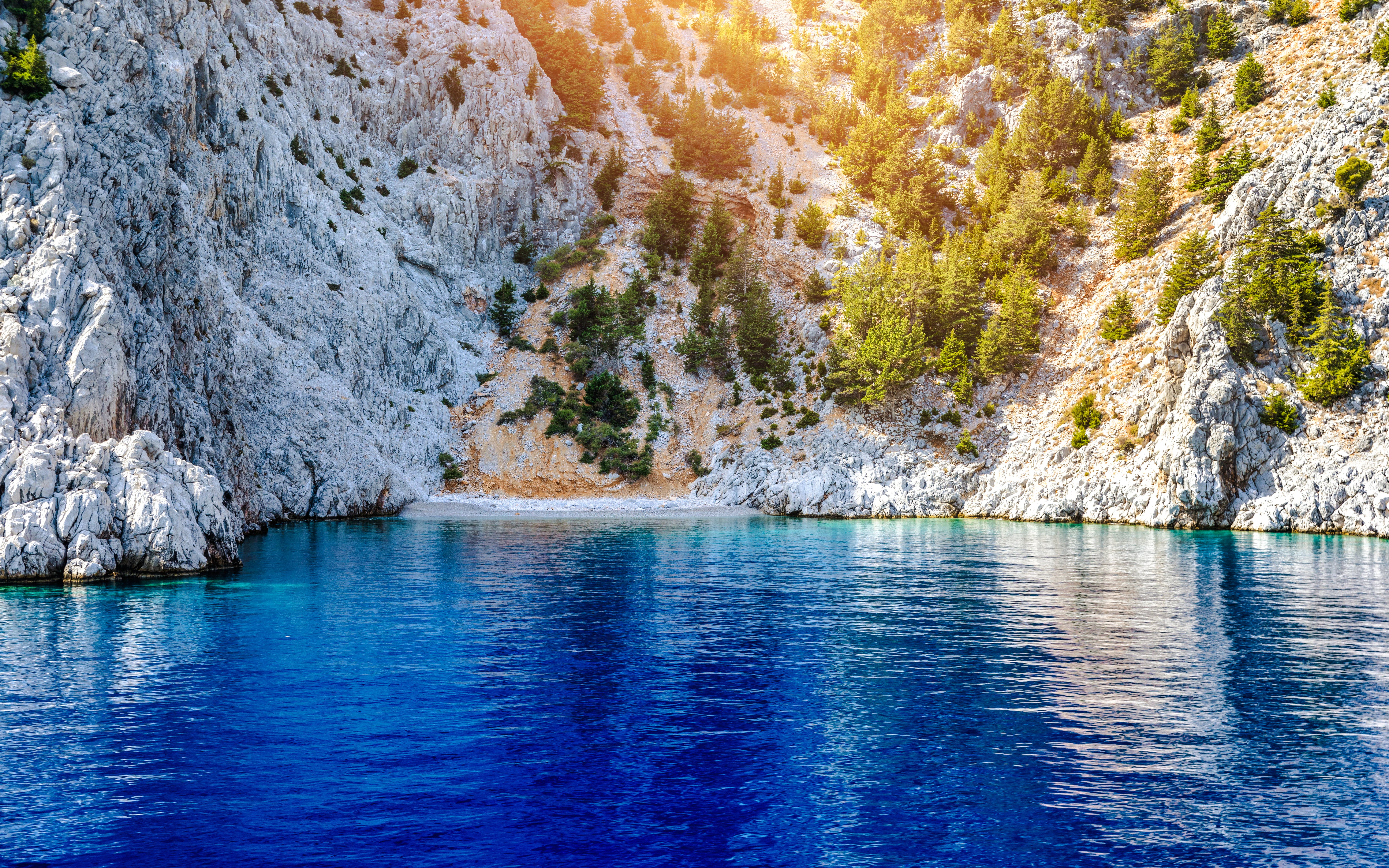 Rocky cliffs and clear blue water at St George's Bay, Symi Island, Rhodes.