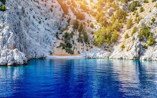 Rocky cliffs and clear blue water at St George's Bay, Symi Island, Rhodes.