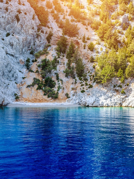 Rocky cliffs and clear blue water at St George's Bay, Symi Island, Rhodes.