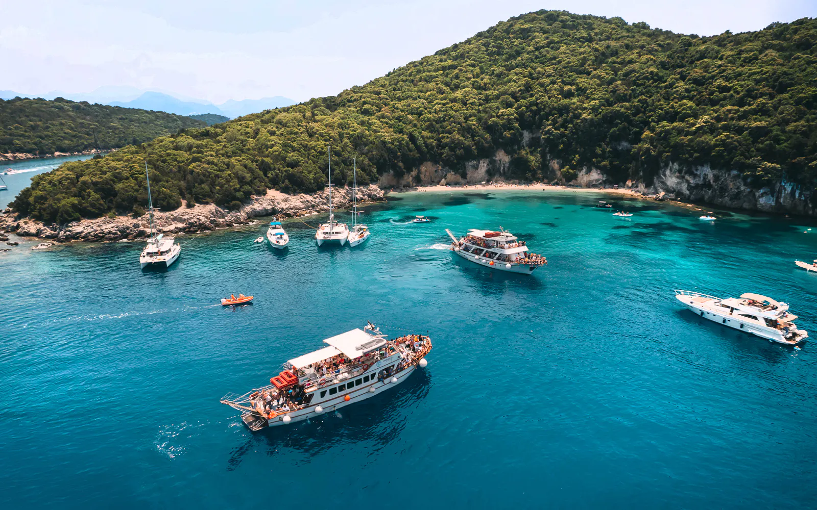 Cruise boats in Blue Lagoon near lush hills on Papanikolis tour from Benitses/Lefkimmi.