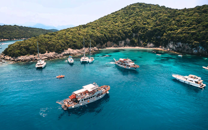 Cruise boats in Blue Lagoon near lush hills on Papanikolis tour from Benitses/Lefkimmi.